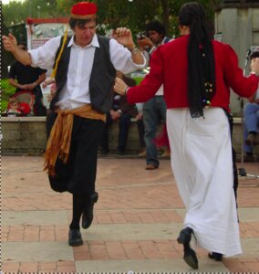 Giorgio Parisi wearing traditional Greek costume dances with another person in the street
