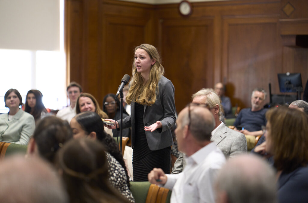 A woman in an audience standing asking a question.