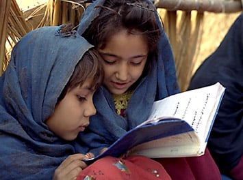 Two girls share a textbook.