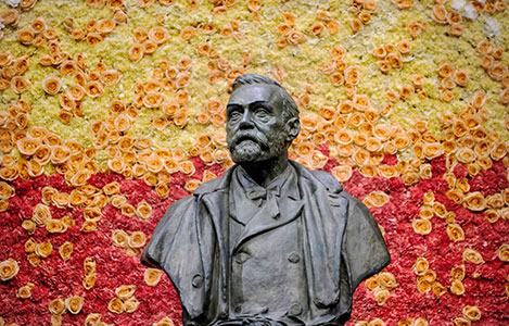 A bust of Alfred Nobel, surrounded by a beautiful wall of flowers